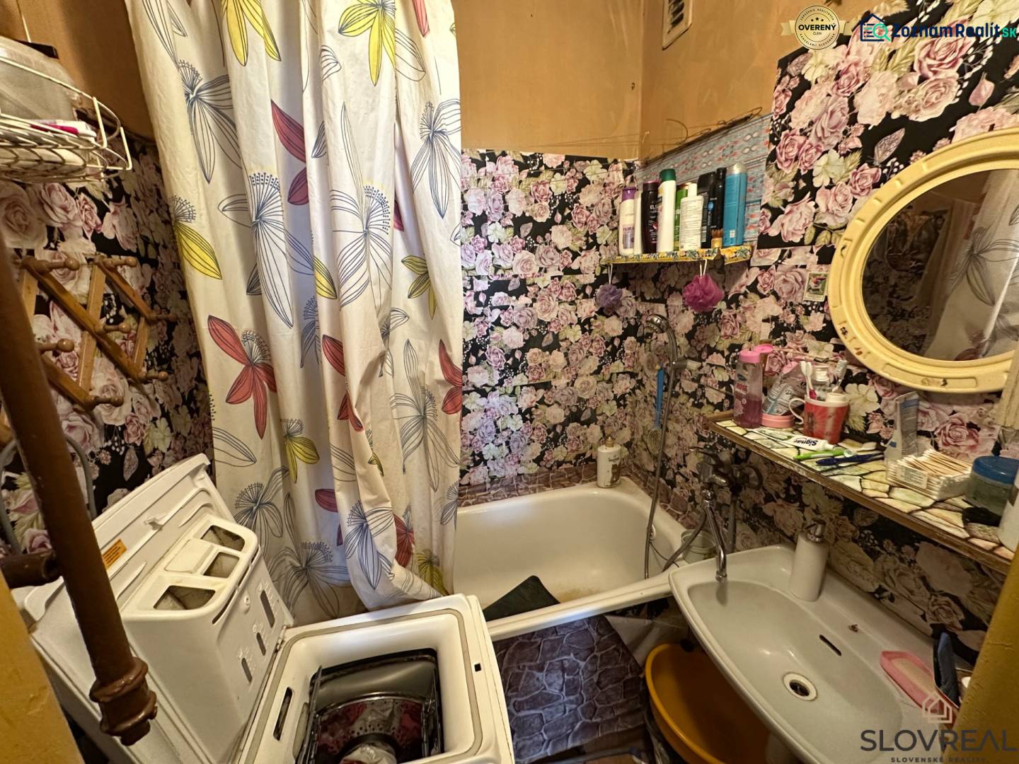 A bathroom with floral wallpaper, a washing machine, and a sink in a 3-room apartment.