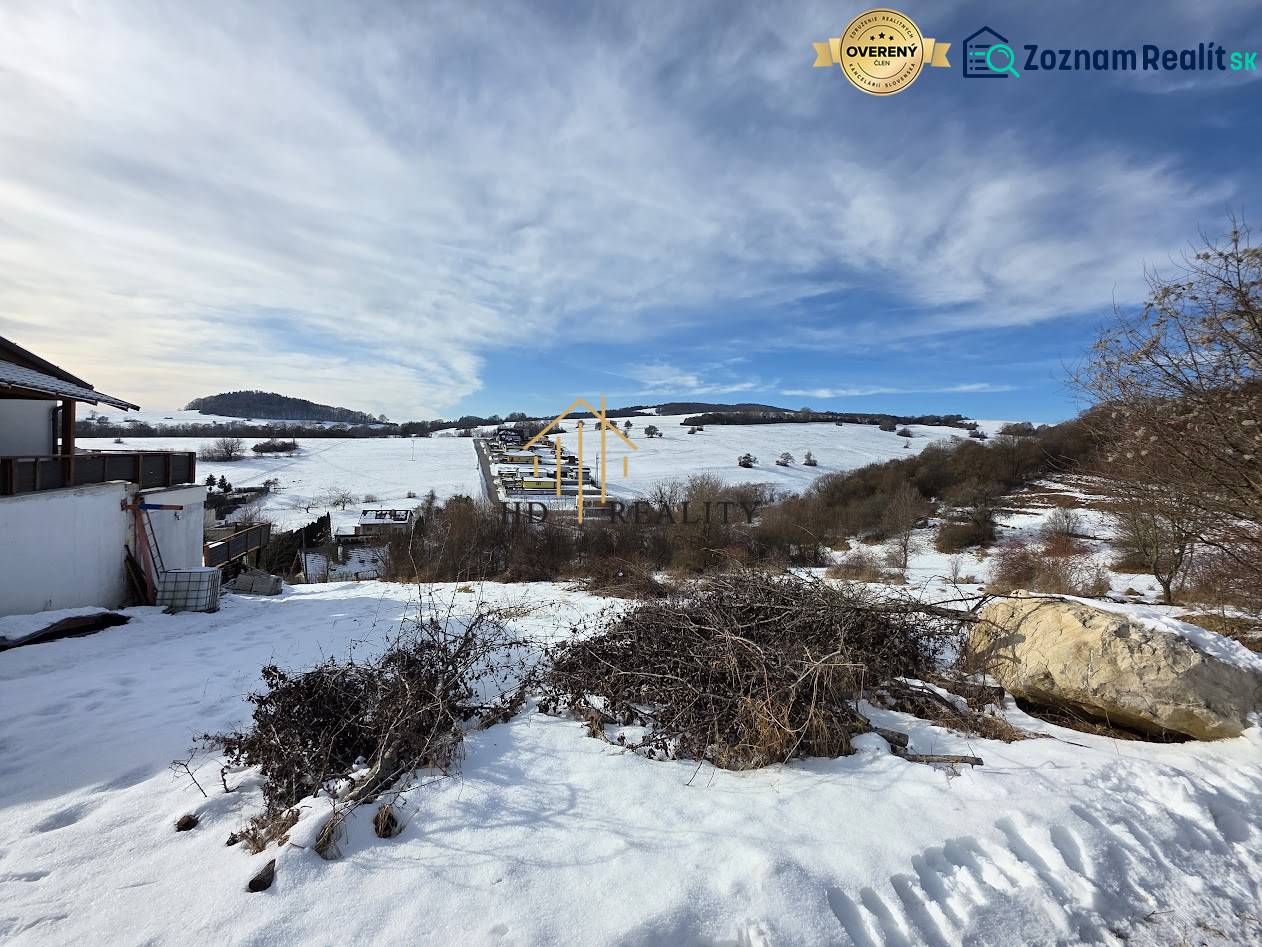 A snowy landscape with residential plots in Horná Mičiná, set in gentle hills.