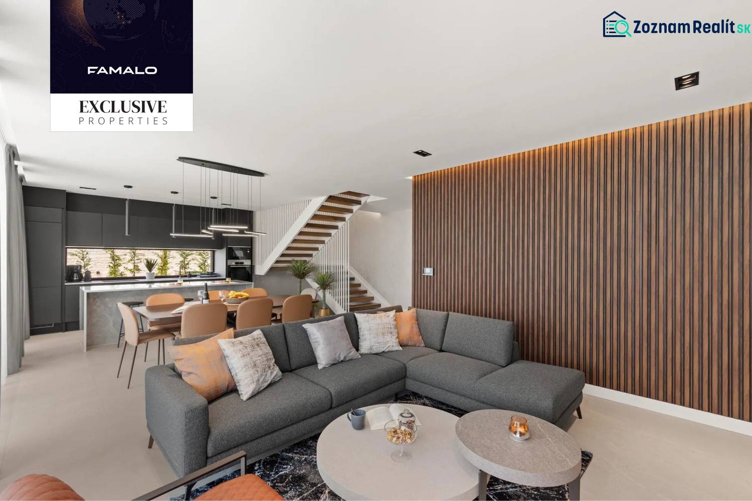 Interior of a villa with a corner sofa, open kitchen, and wooden decor on the wall.