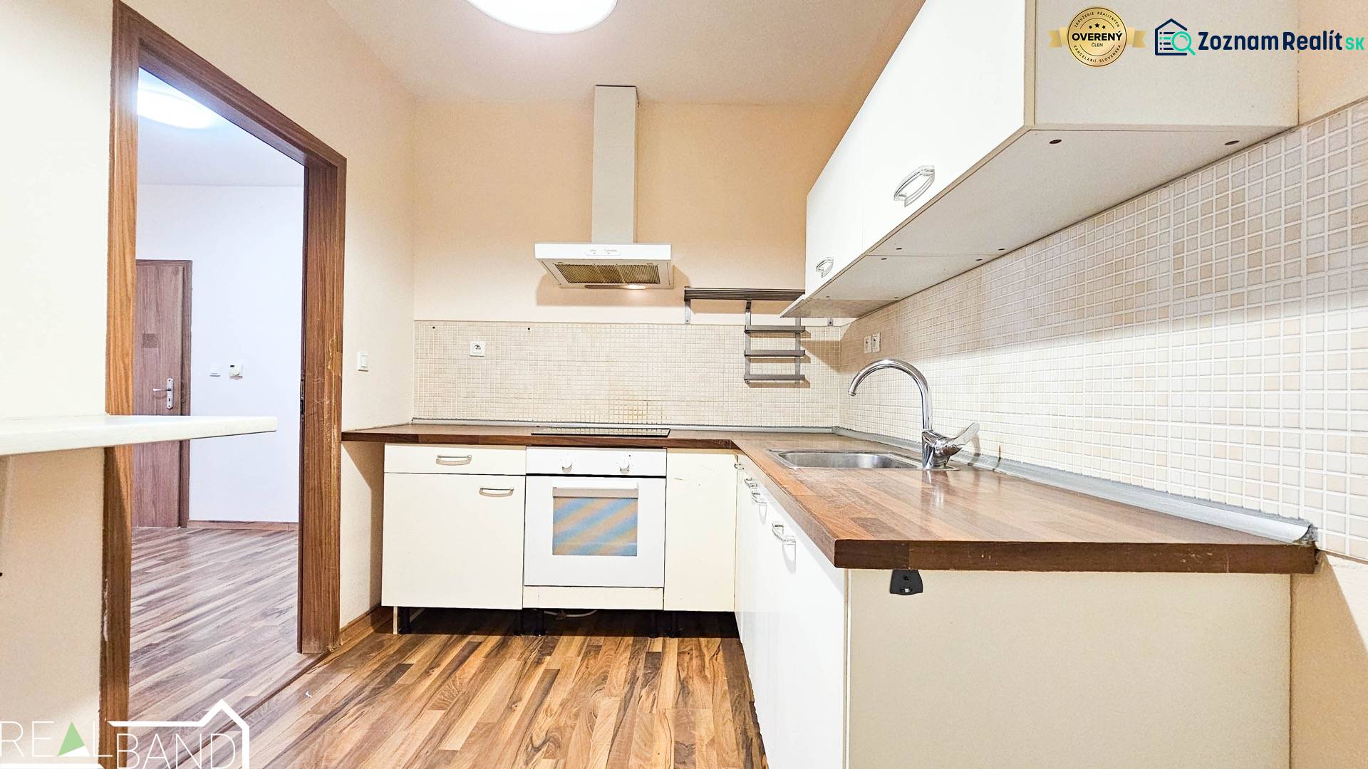 A kitchen in a 2-room apartment with tiles and a wooden decor floor.