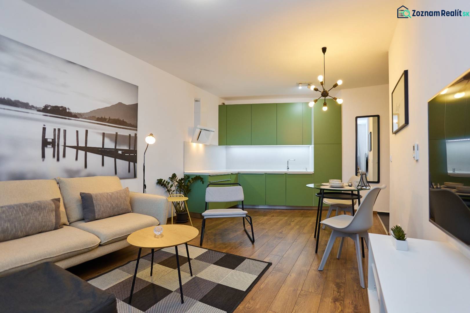 Living room with kitchen in a 2-room apartment, wooden decor flooring, green cabinets.