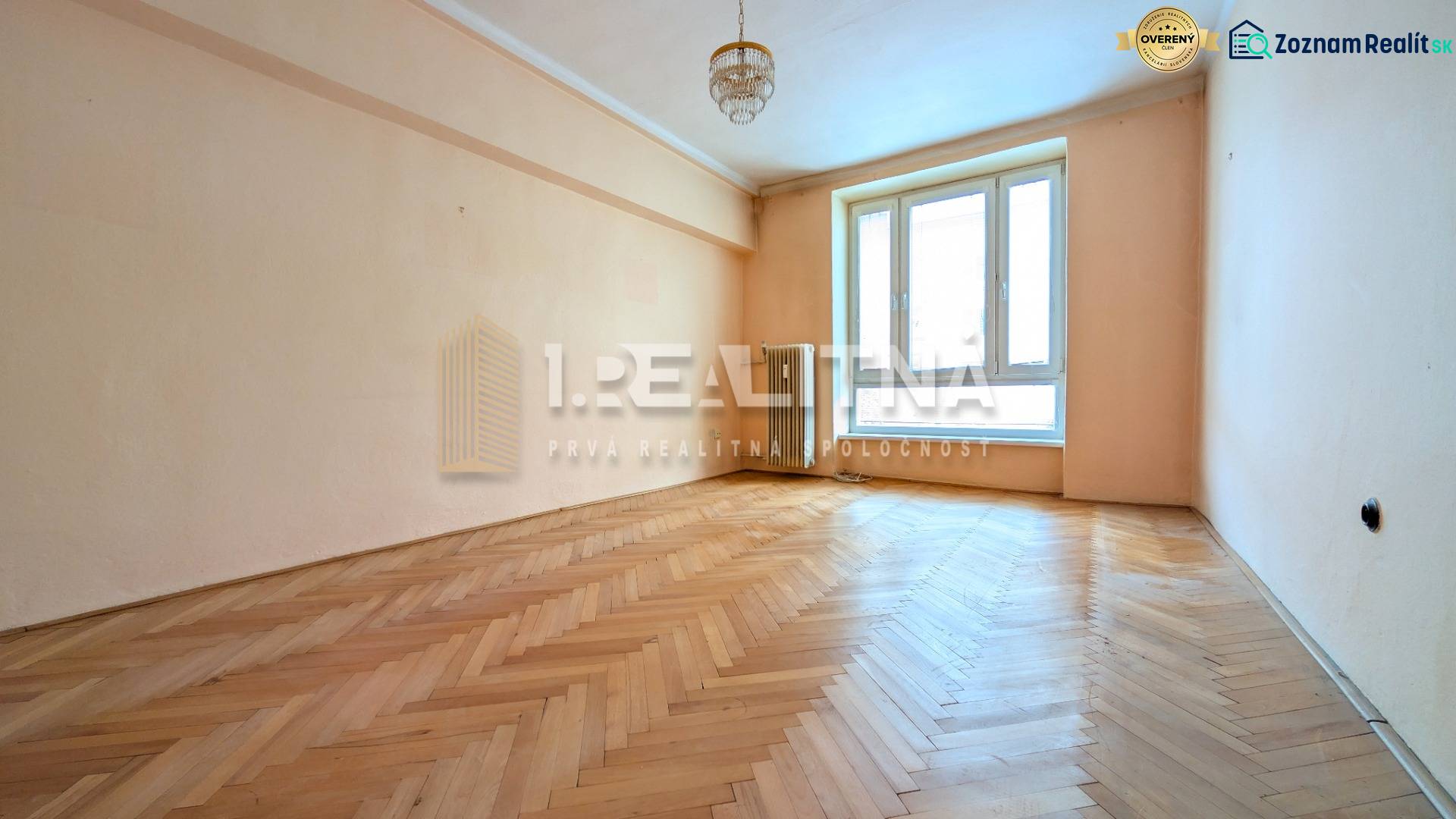 A bright room in a 2-room apartment with a wood-patterned floor and a large window.