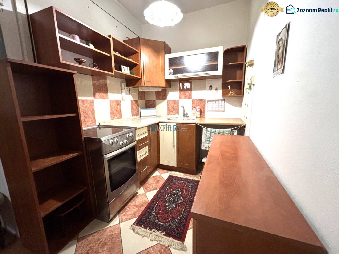 The kitchen in the studio apartment with a wooden decor and red and white tiles.