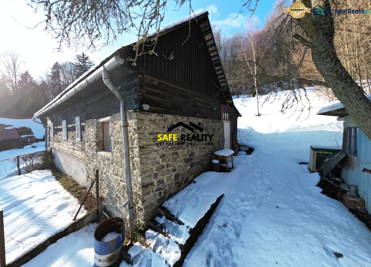 A cottage in Veľké Rovné in a snowy setting with stone walls and a wooden roof.
