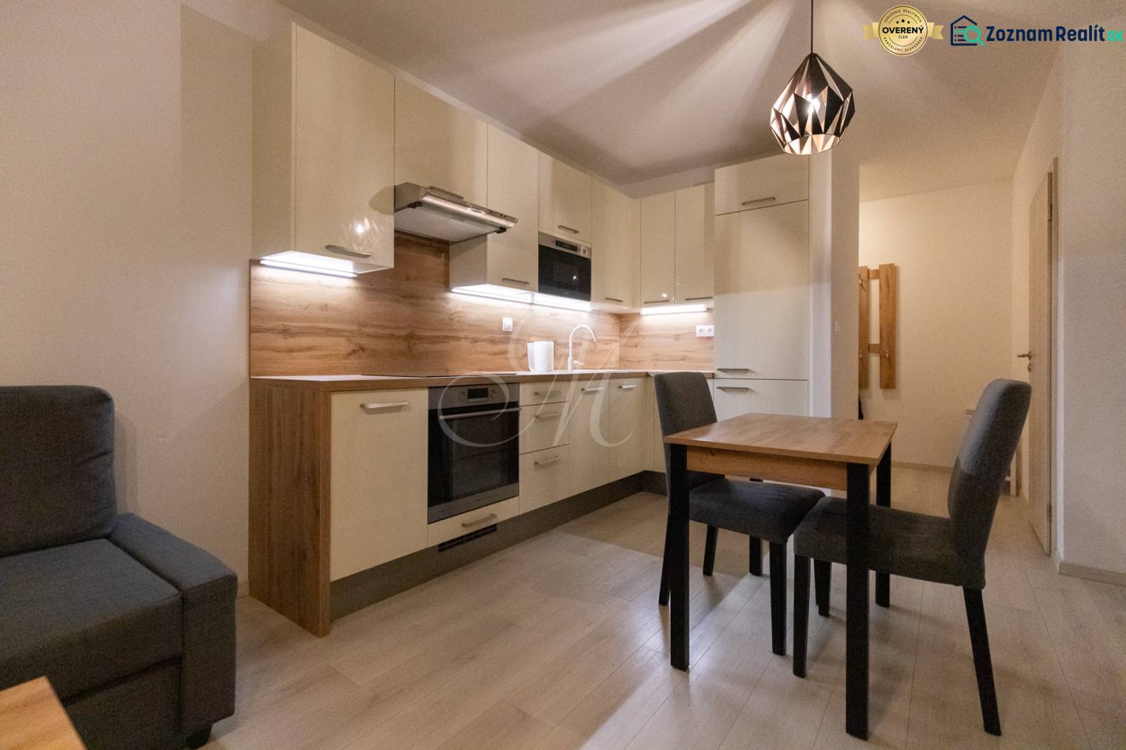 A kitchen in a 2-room apartment with a wooden decor floor and a dining table.