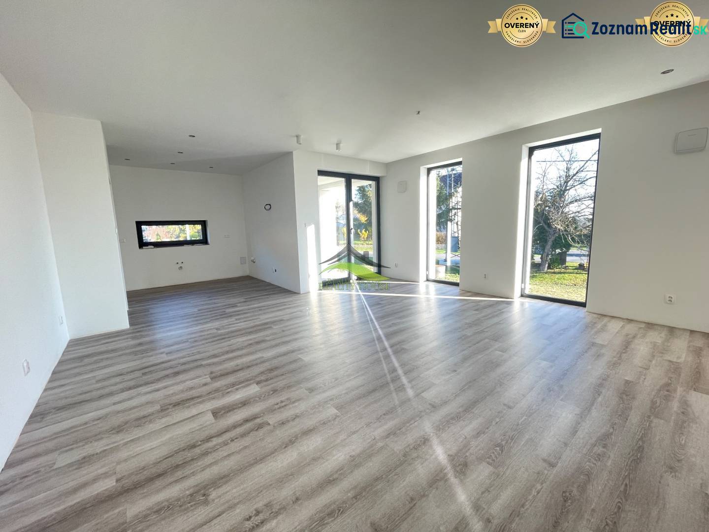 A spacious interior of a family house with a wooden decor floor and large windows.