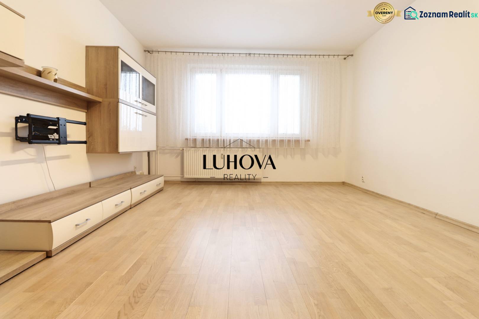 Living room in a three-room apartment with furniture and flooring featuring a wood design.