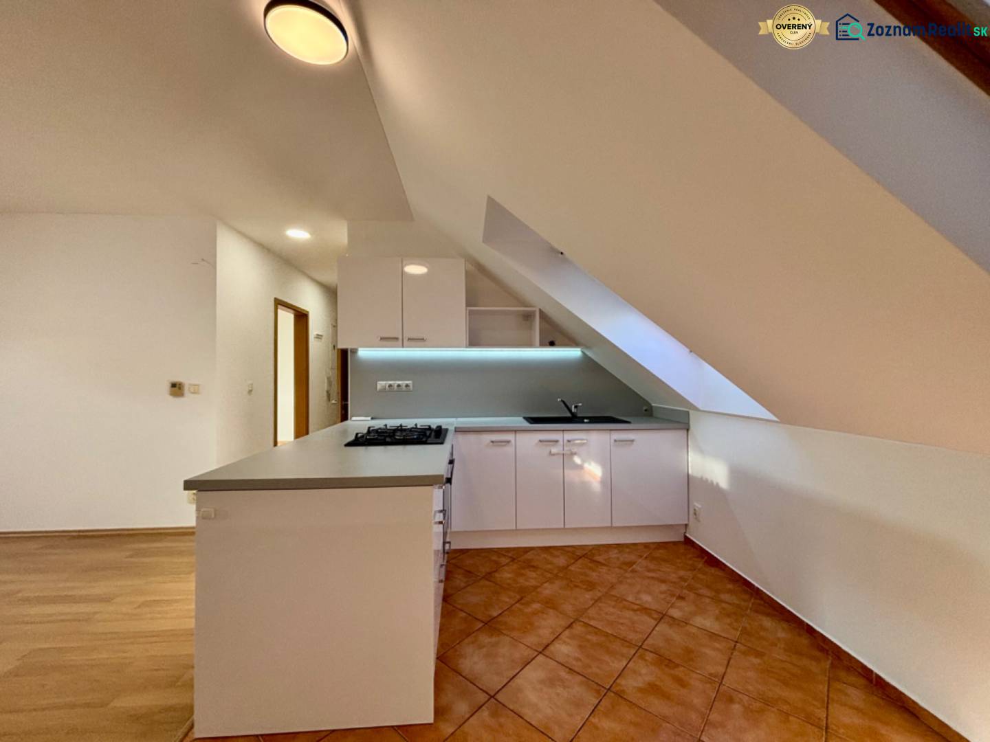 A kitchen in a 2-room apartment with a kitchen unit and a ceramic tile floor.
