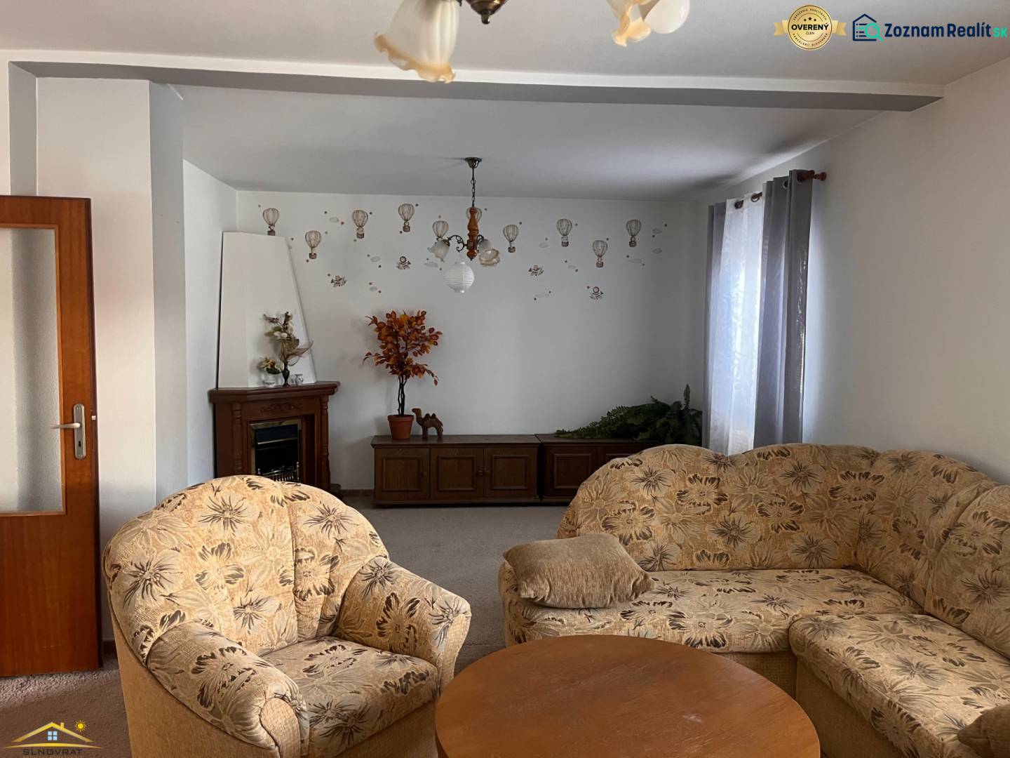 Living room in a family house, with a floral armchair, ornaments, and a fireplace.