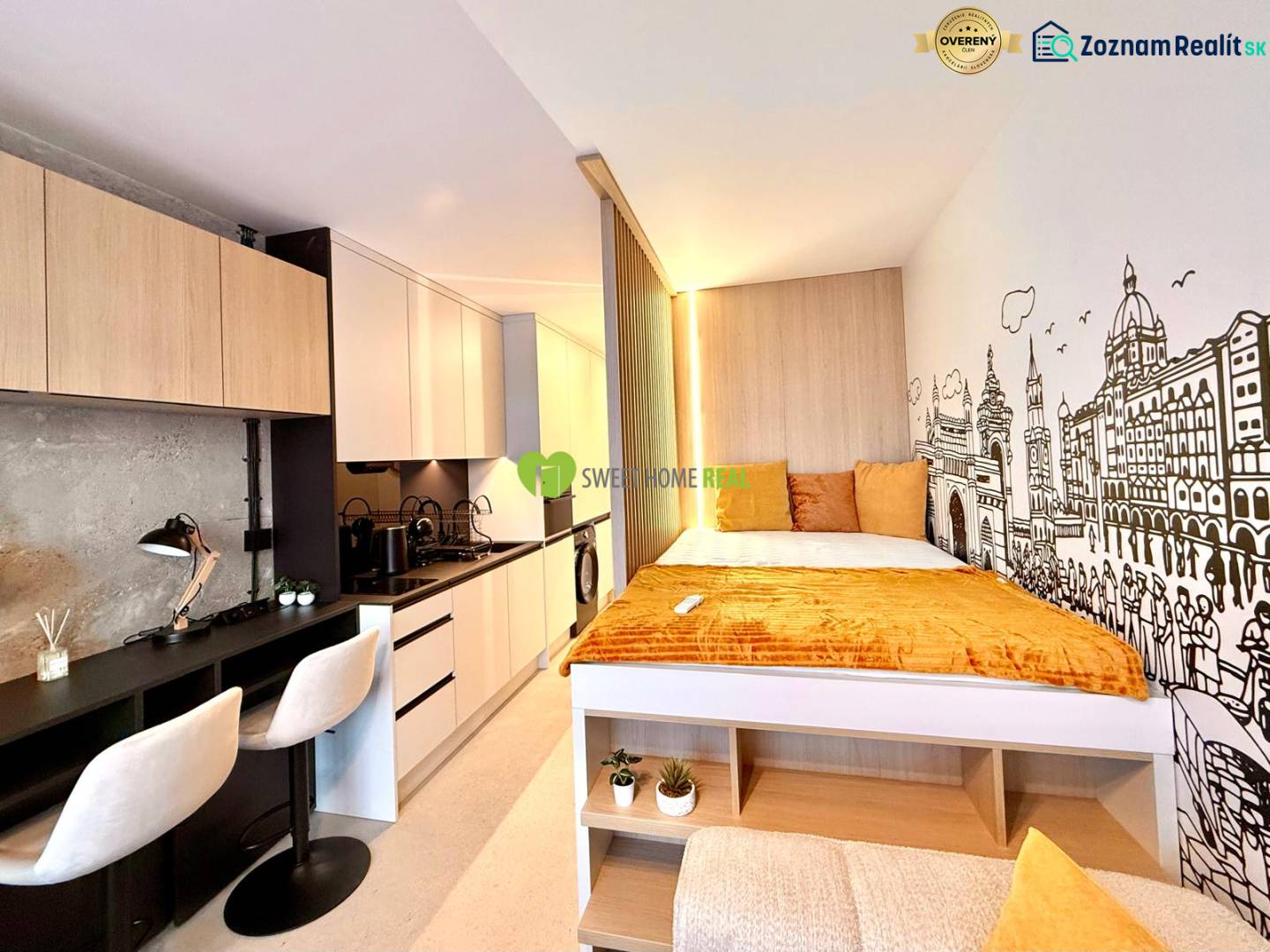 Compact space of a studio apartment with a kitchenette, desk, and bed.