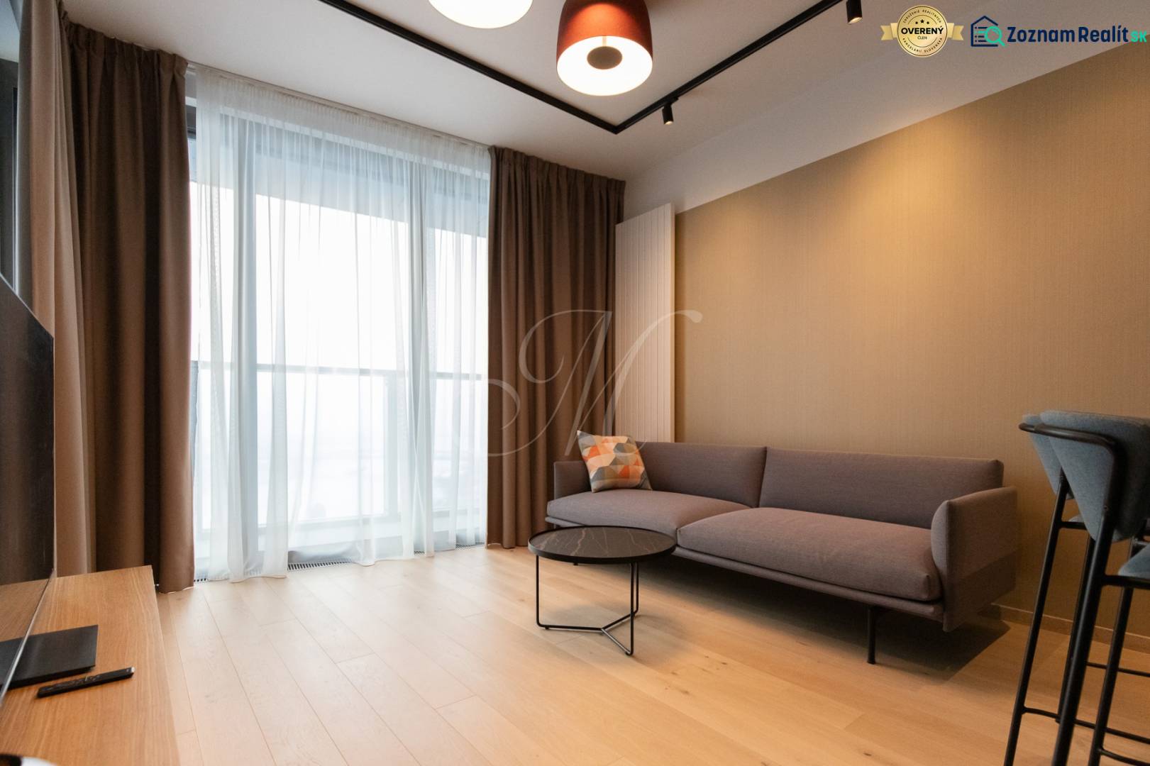 Living room in a two-room apartment with a sofa, coffee table, and wooden decor flooring.