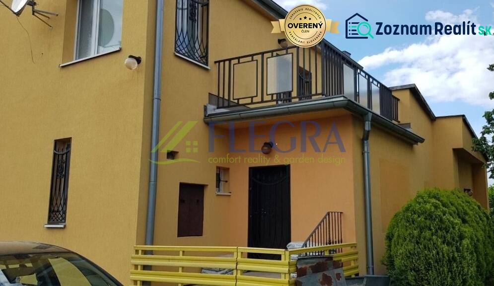 Yellow facade of a family house in Stretavka with a balcony and wrought iron window grilles.