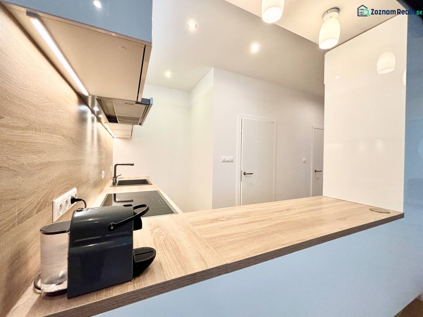 A kitchen in a 3-room apartment with a wooden decor floor and built-in lighting.
