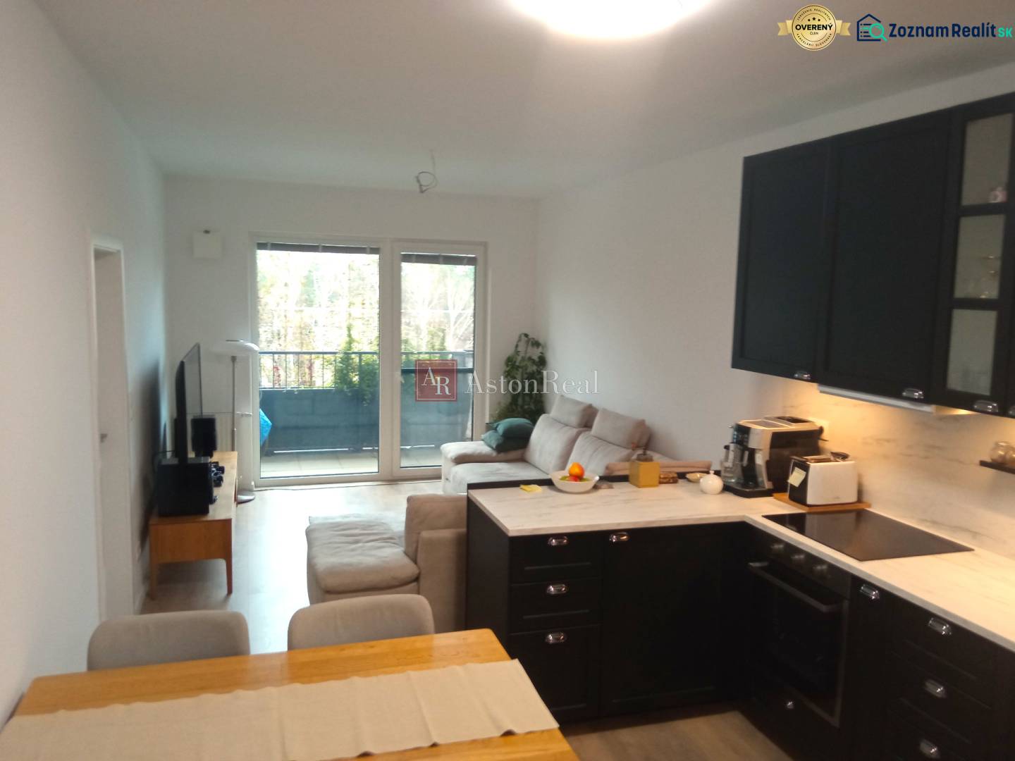 Interior of a 2-room apartment with a kitchen, sofa, and balcony, floor with wood decor.