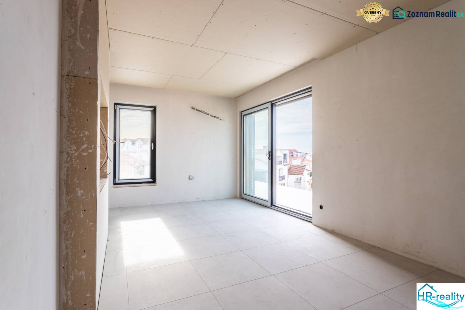 A room under construction with tiles and large windows in a 3-room apartment.