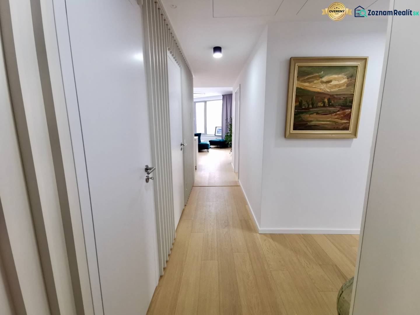 A hallway in a 3-room apartment with a wooden decor floor and a picture on the wall.