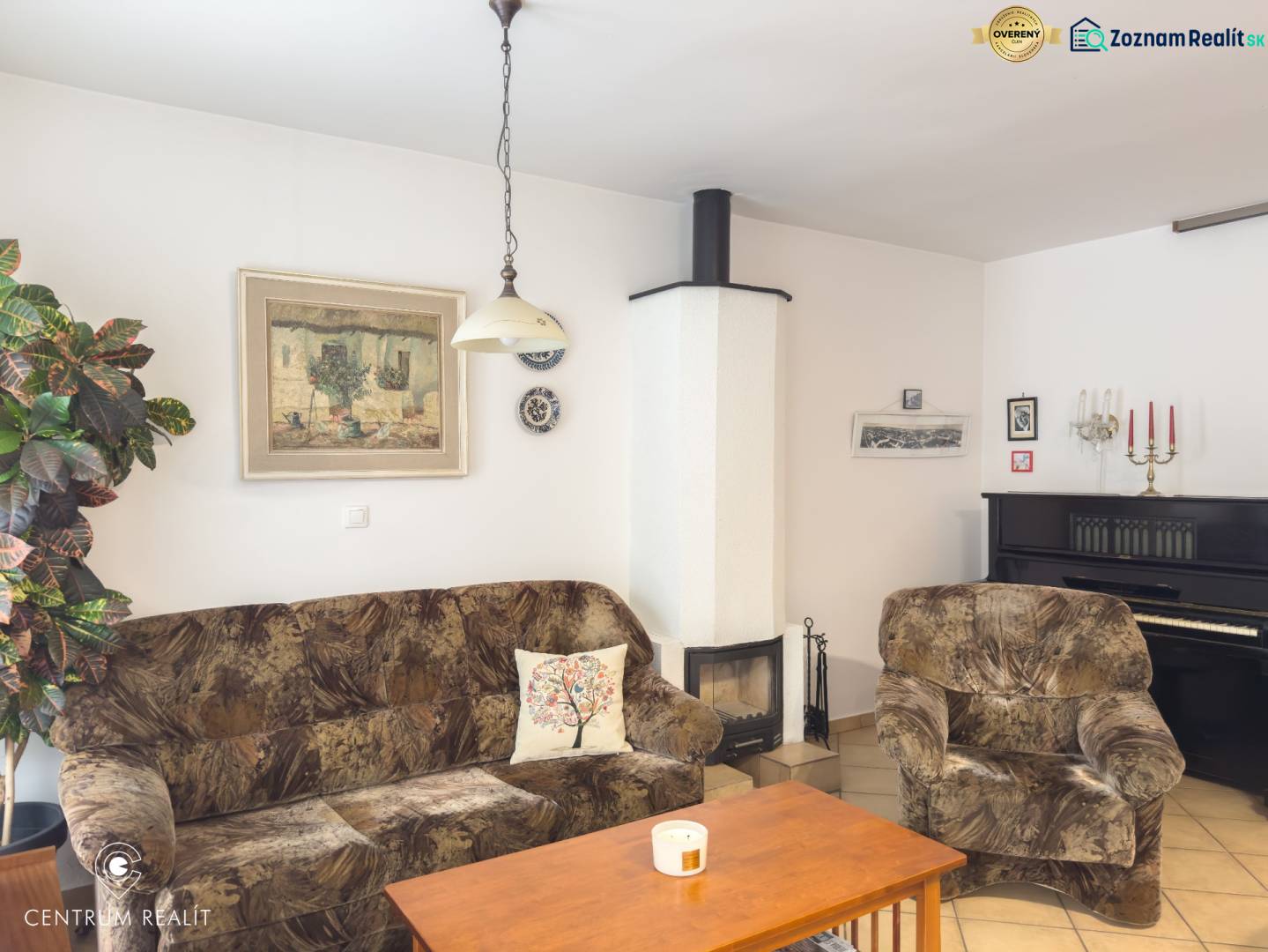 Living room in a family house with a sofa, fireplace, piano, and wall decorations.