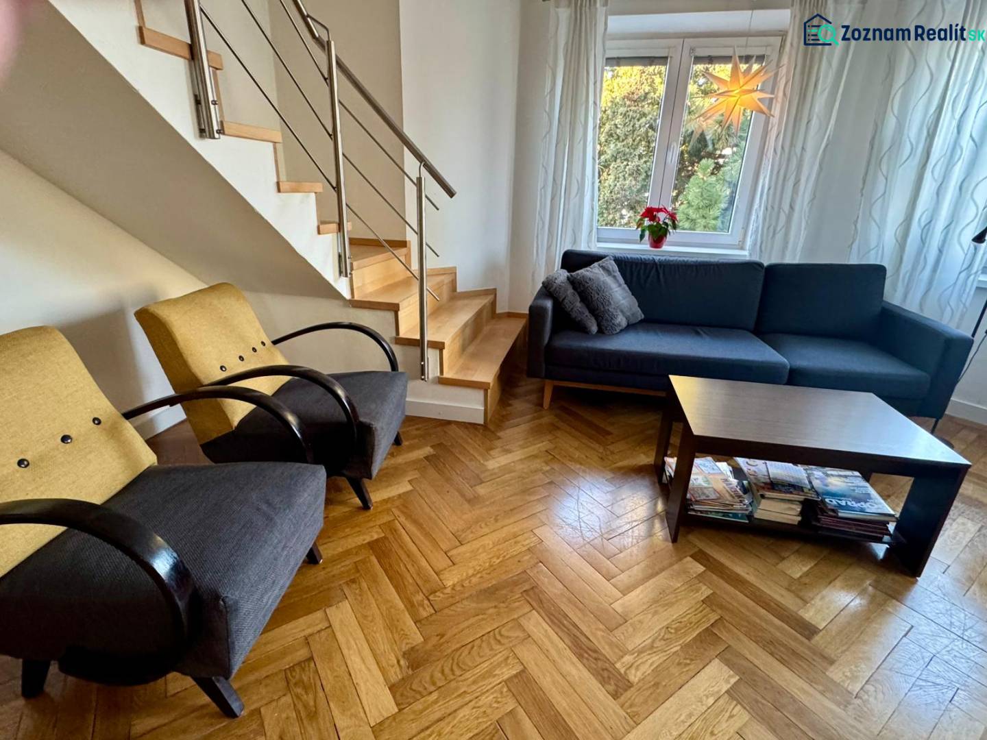 Living room in a 3-room apartment with a wooden decor floor, staircase, sofa, and armchairs.