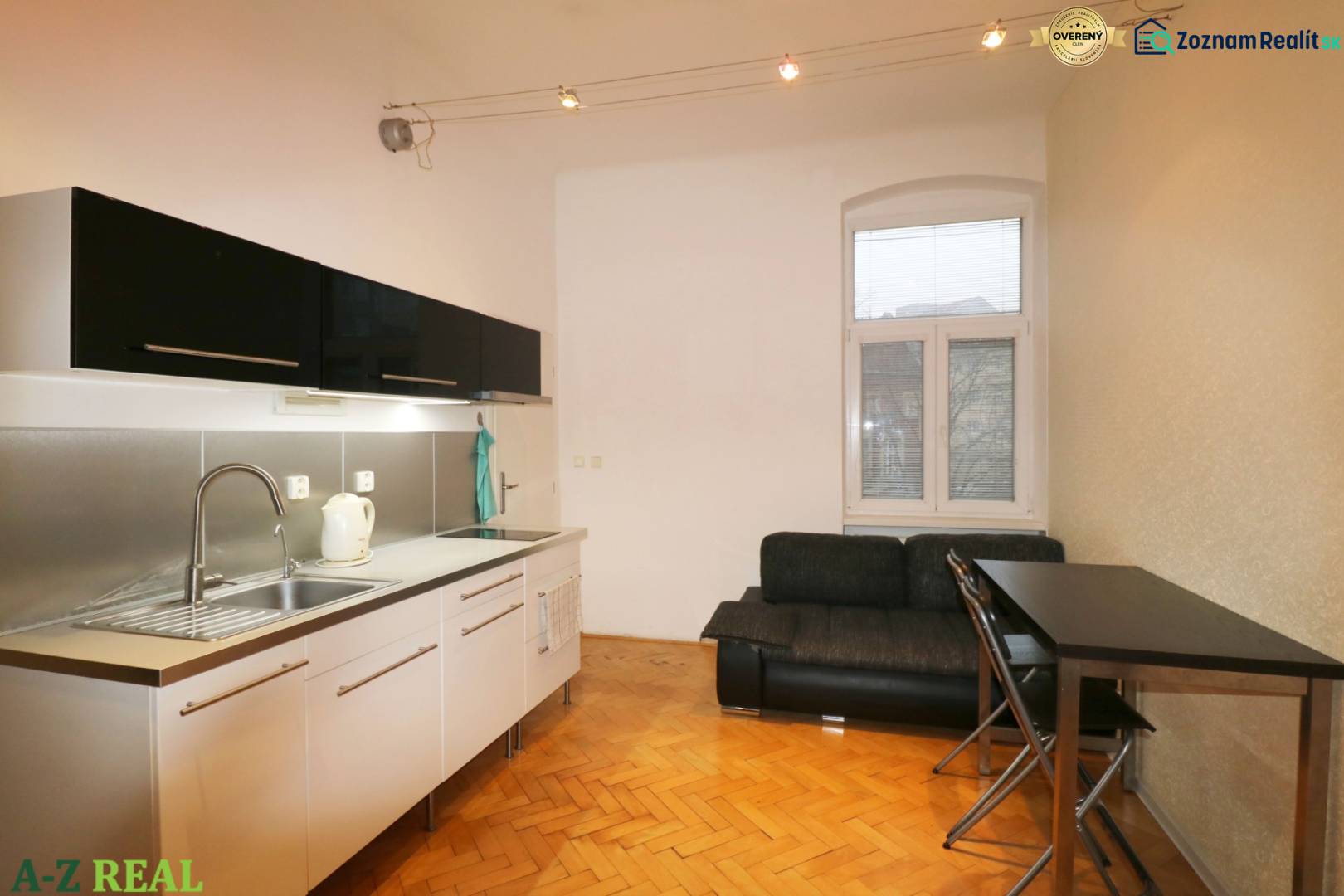 A kitchen in a 3-room apartment with a wooden decor floor and a sofa next to the dining table.