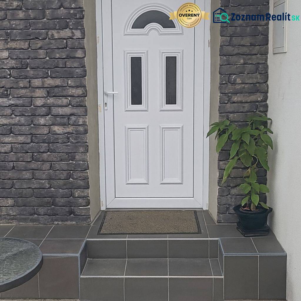 Entrance to a family house in Horné Saliby, white door, brick cladding, stairs with greenery.