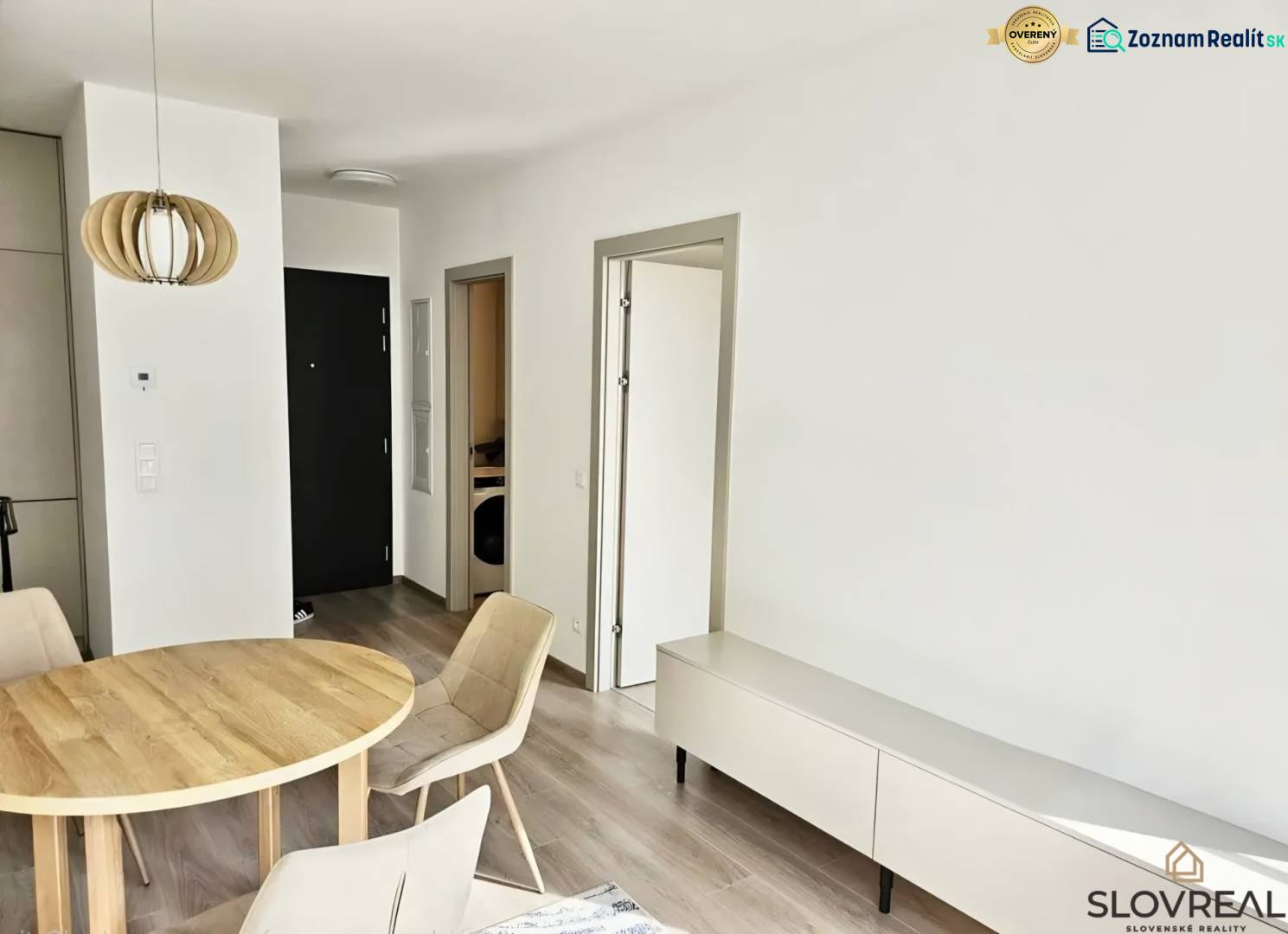 Dining table and chairs in a studio apartment with a wood-patterned floor.
