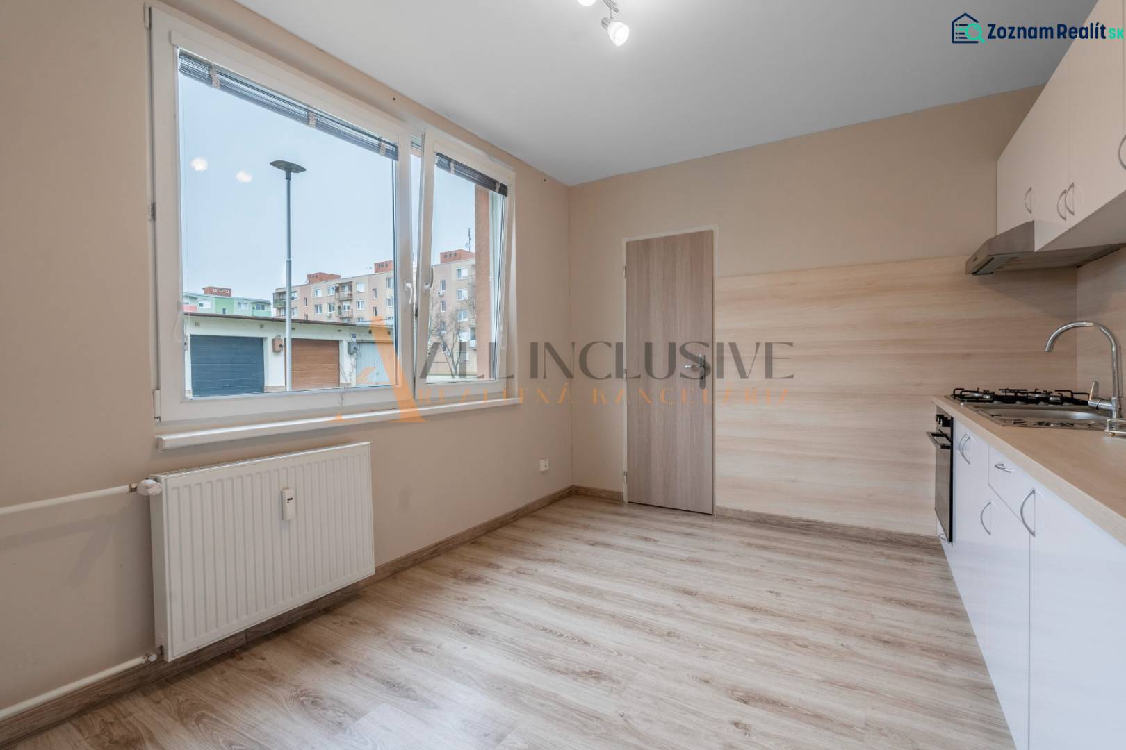 A kitchen in a one-room apartment with a wooden decor floor.