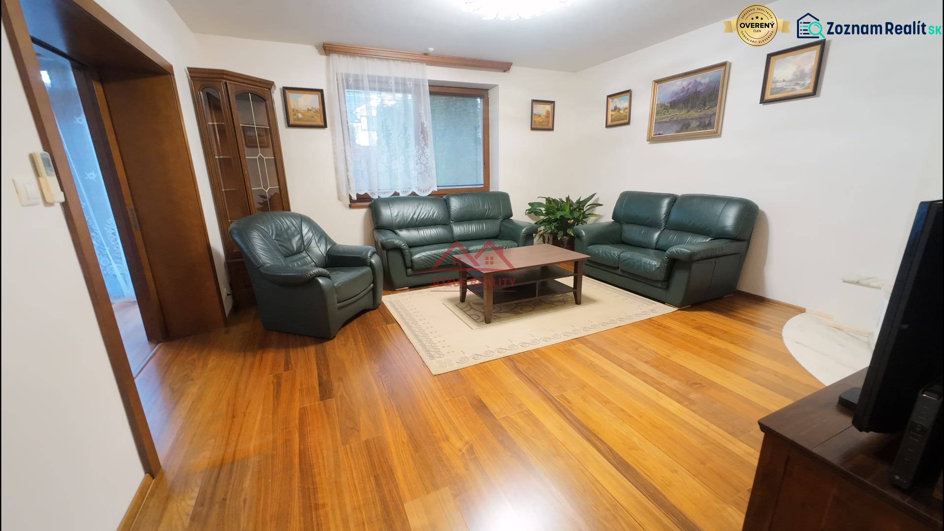 Living room in a family house with leather furniture and wood-patterned flooring.