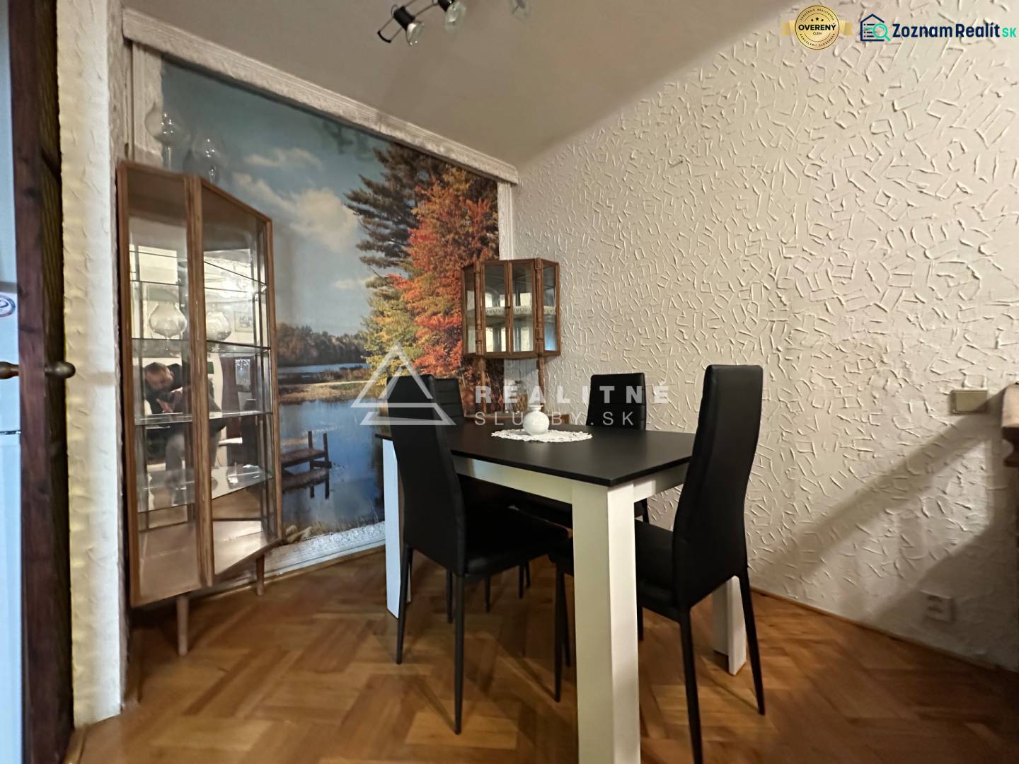 Dining room in a 3-room apartment with a wall mural and wood-patterned flooring.