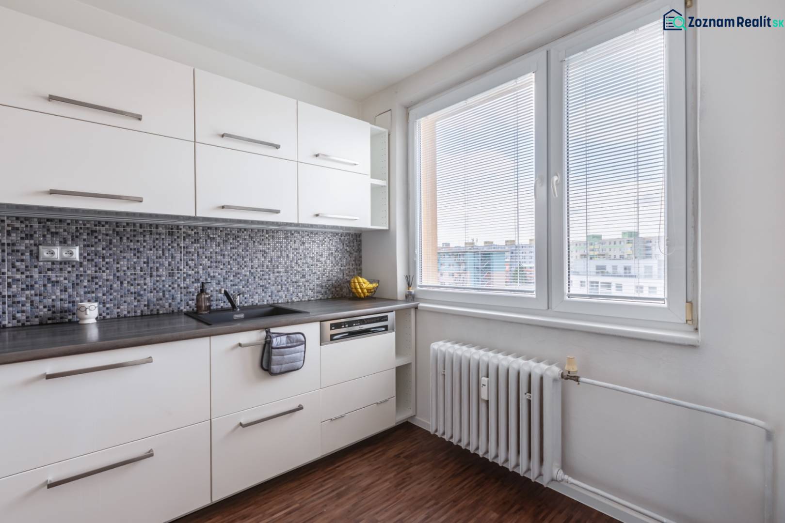 A kitchen in a 3-room apartment with a wood-patterned floor and a large window.