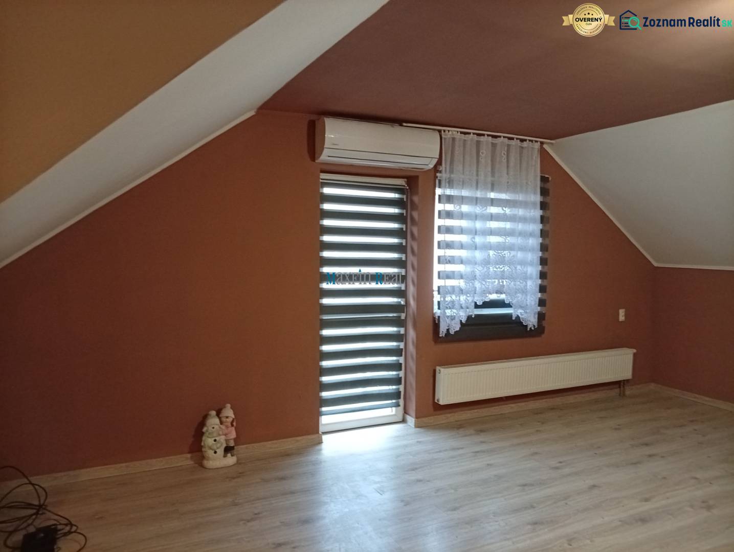 Attic room with air conditioning and wood-patterned flooring in a family house.