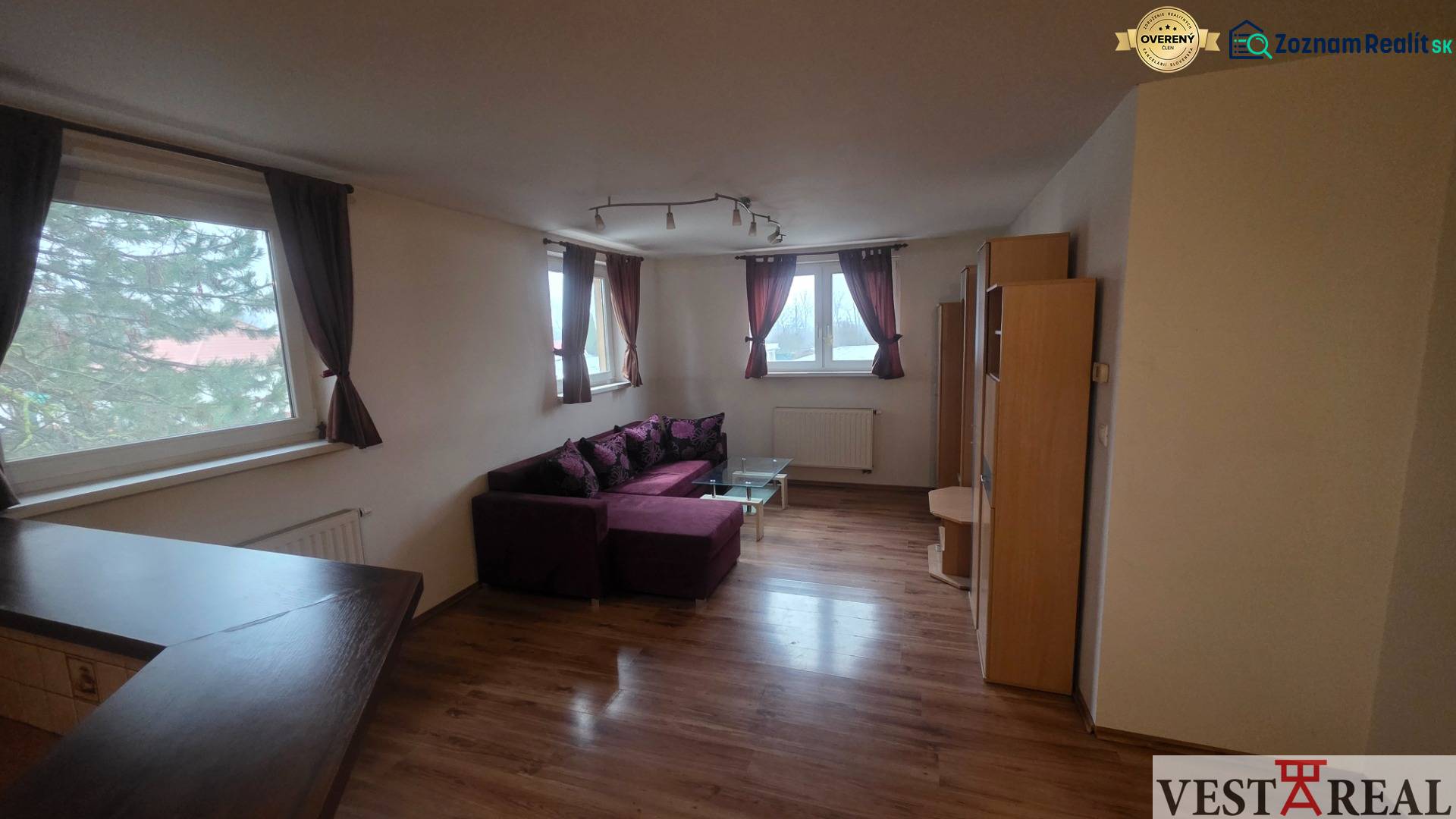 Living room with a purple sofa, wood-patterned floor, 3-room apartment.