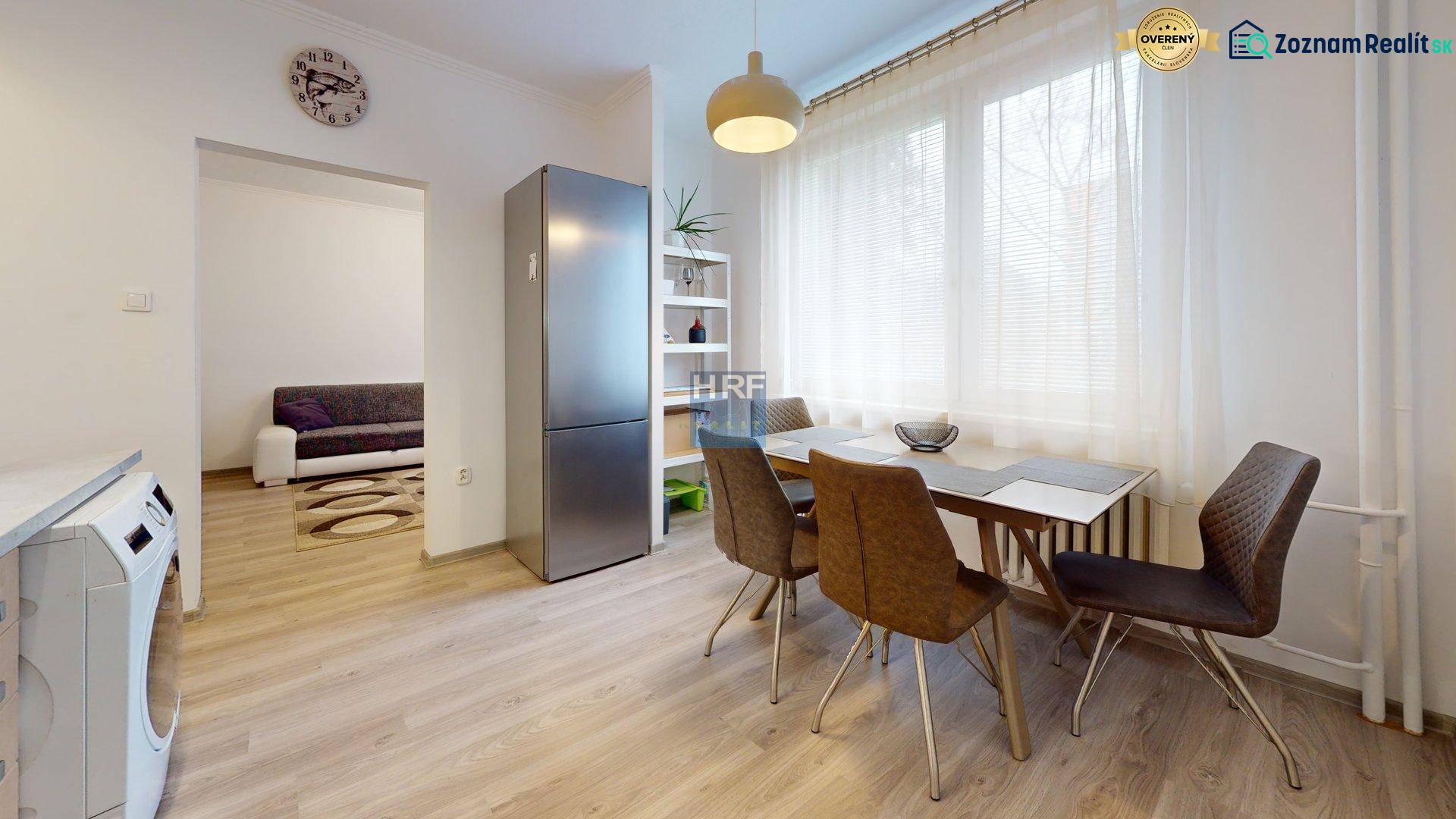 Kitchen of a 2-room apartment with a wooden decor floor, dining table, and refrigerator.