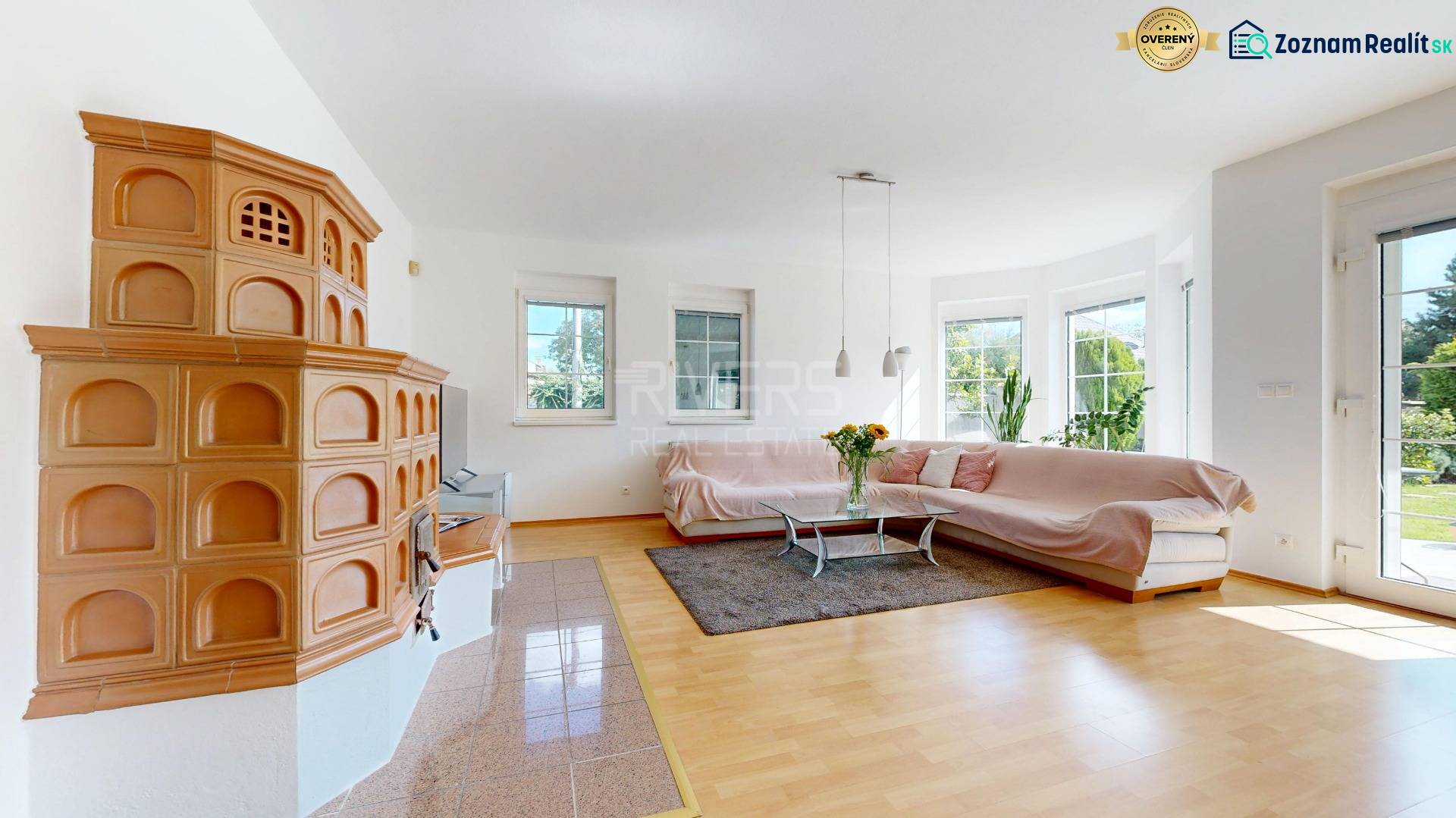 Living room in a family house with a tiled stove, sofa, and wooden decor flooring.