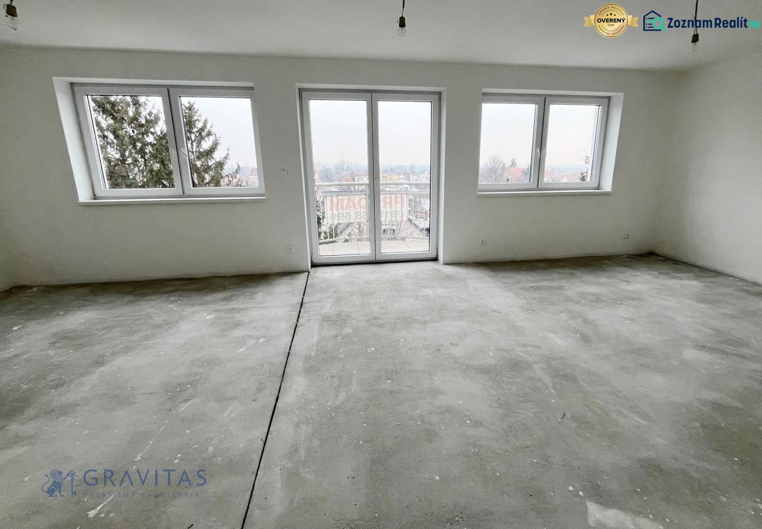 A spacious room with large windows in a 3-room apartment, white walls, and a concrete floor.