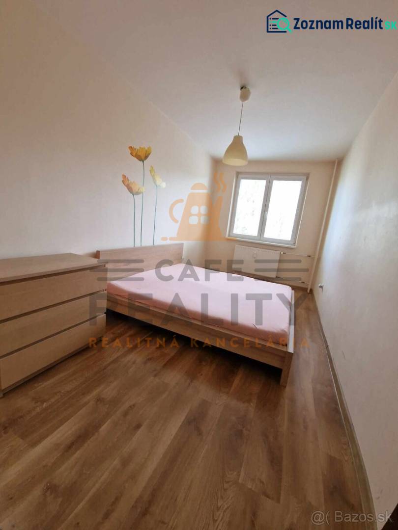 A bedroom in a two-room apartment with a wooden decor floor and a floral motif on the wall.