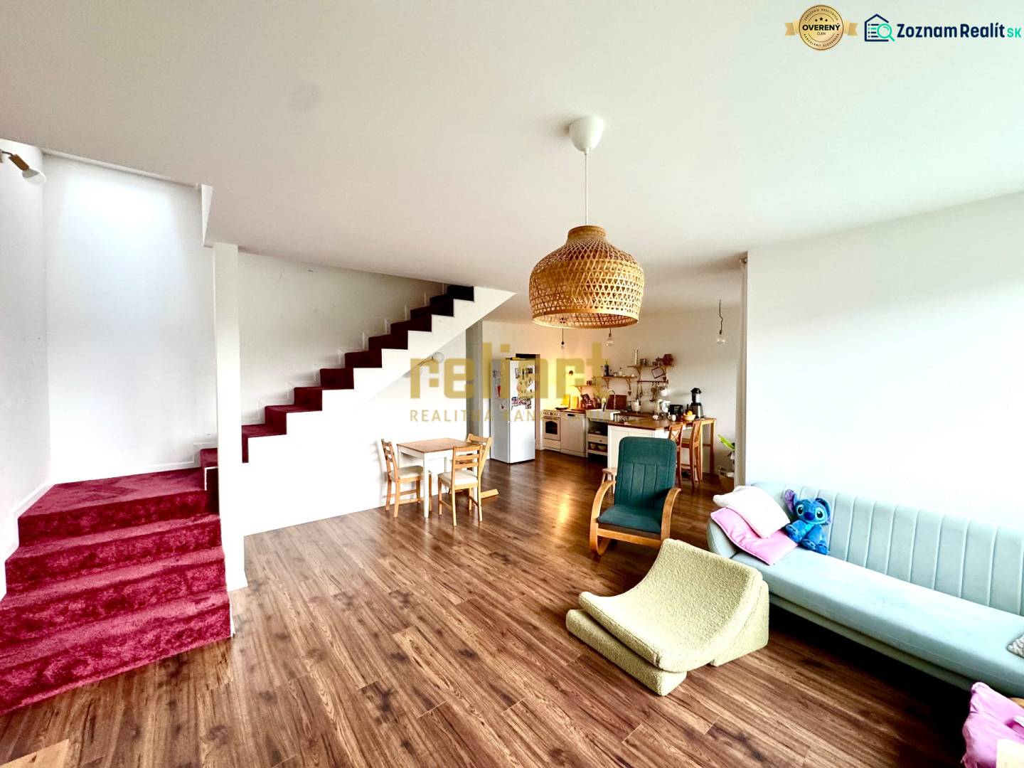 Living room with wood-patterned flooring, staircase, and kitchen in a family house.