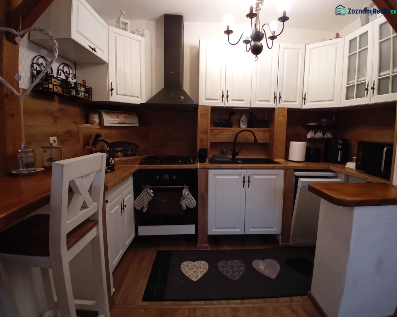 A kitchen in a family house with white cabinets and a wooden decor floor.