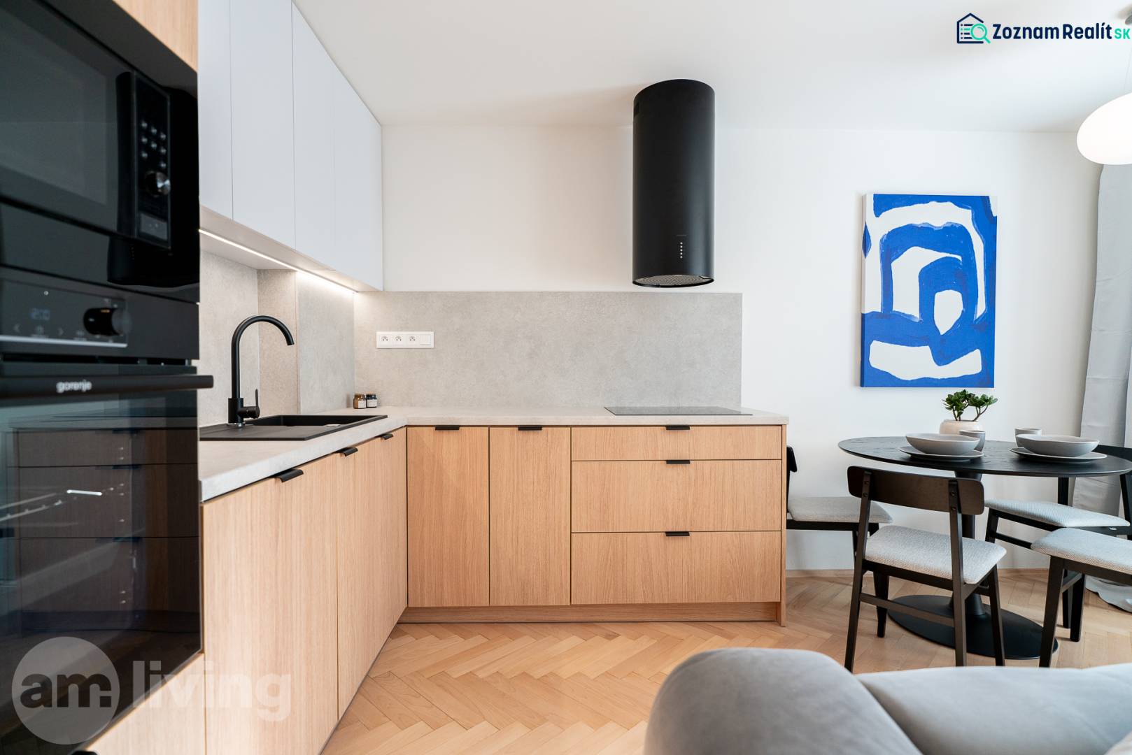 A kitchen with a wood-patterned floor, wooden cabinets, and a dining table in a three-room apartment.