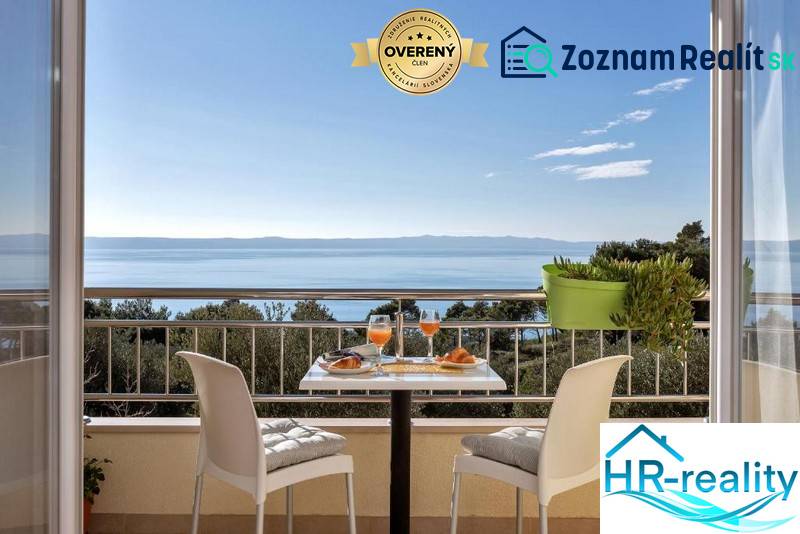 The balcony of a 3-room apartment in Makarska with a sea view and a table with drinks.