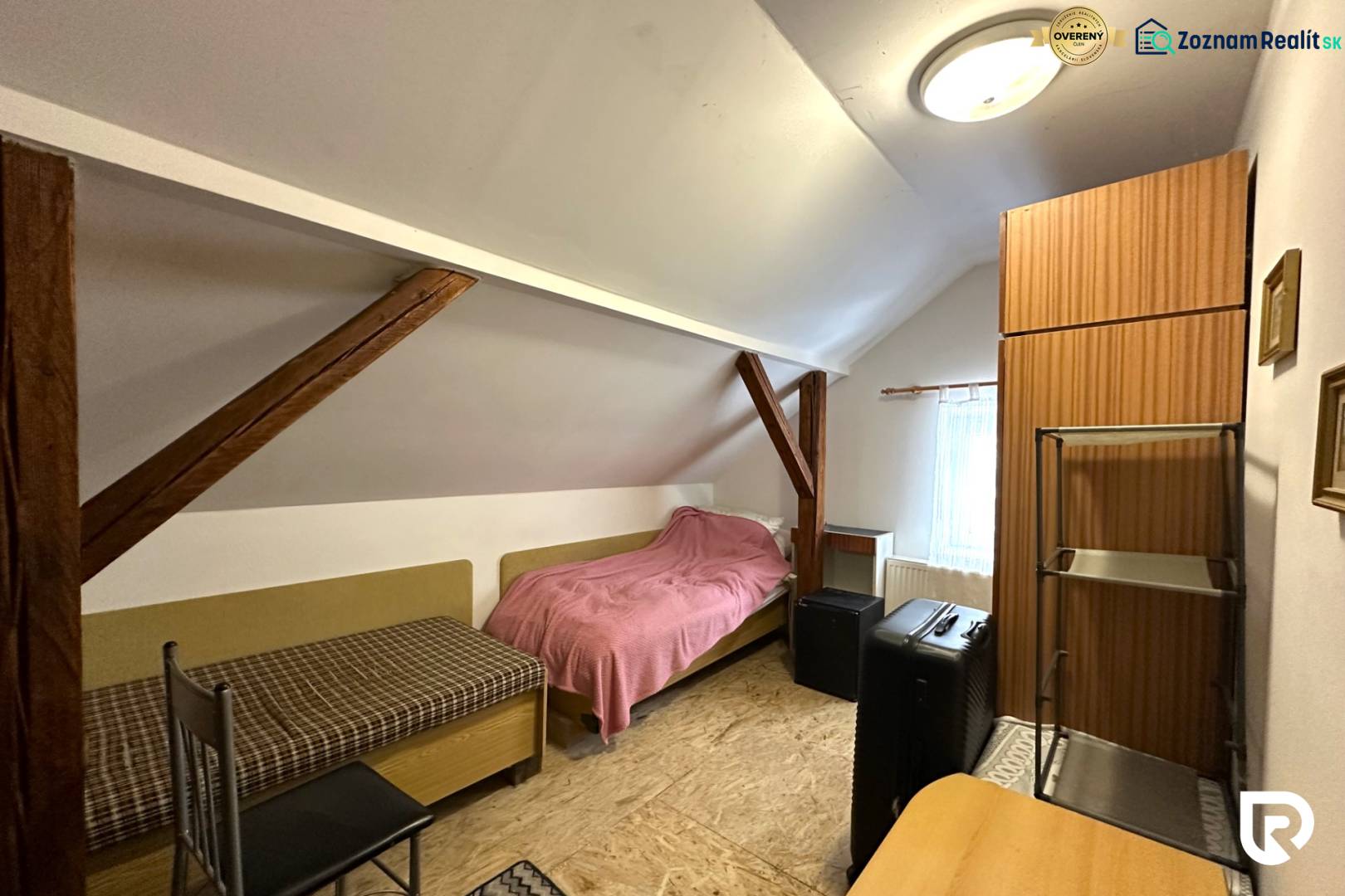 An attic room in a family house with simple furniture and roof beams.