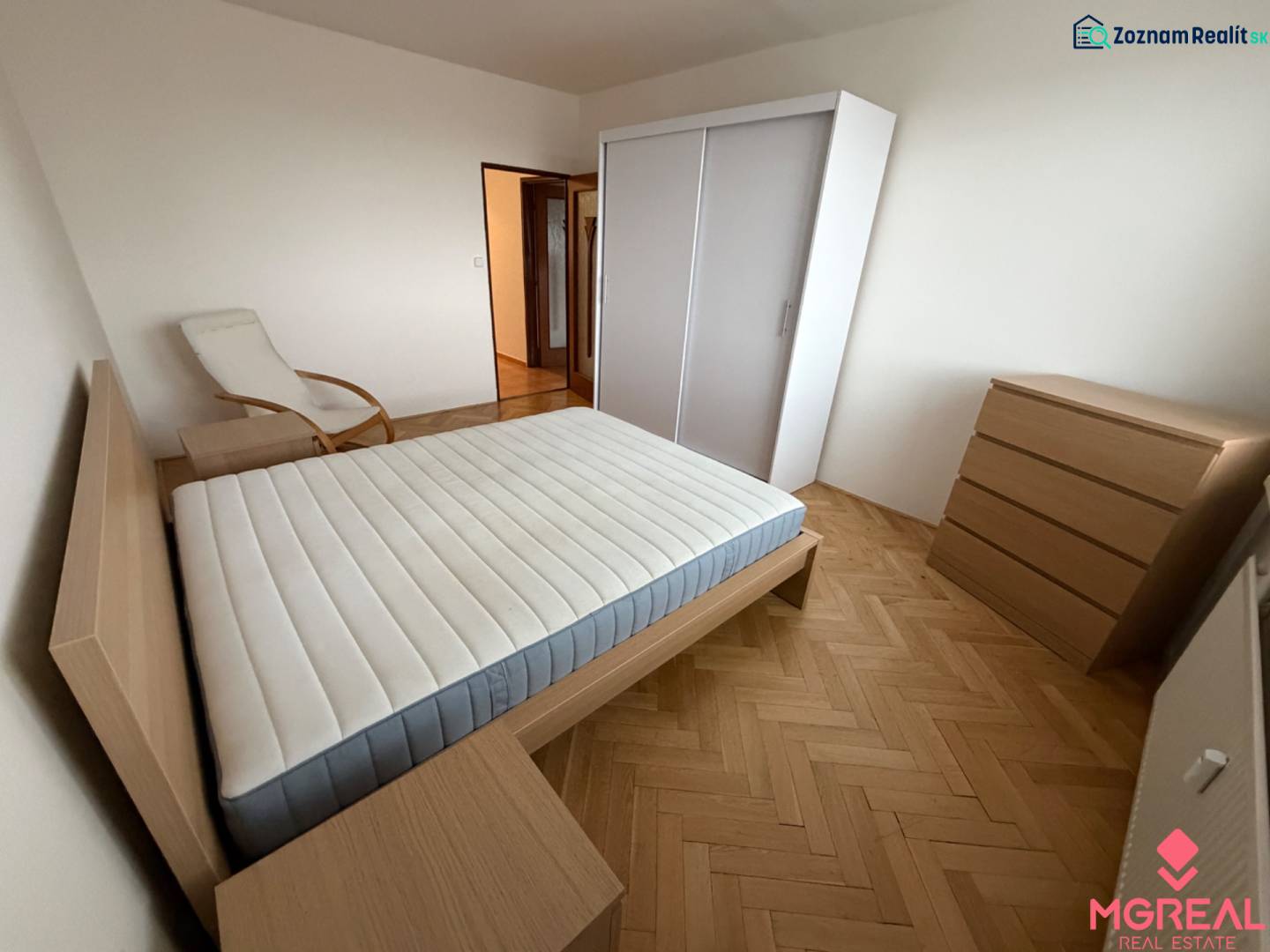 Bedroom with a bed and wooden decor flooring in a 3-room apartment.