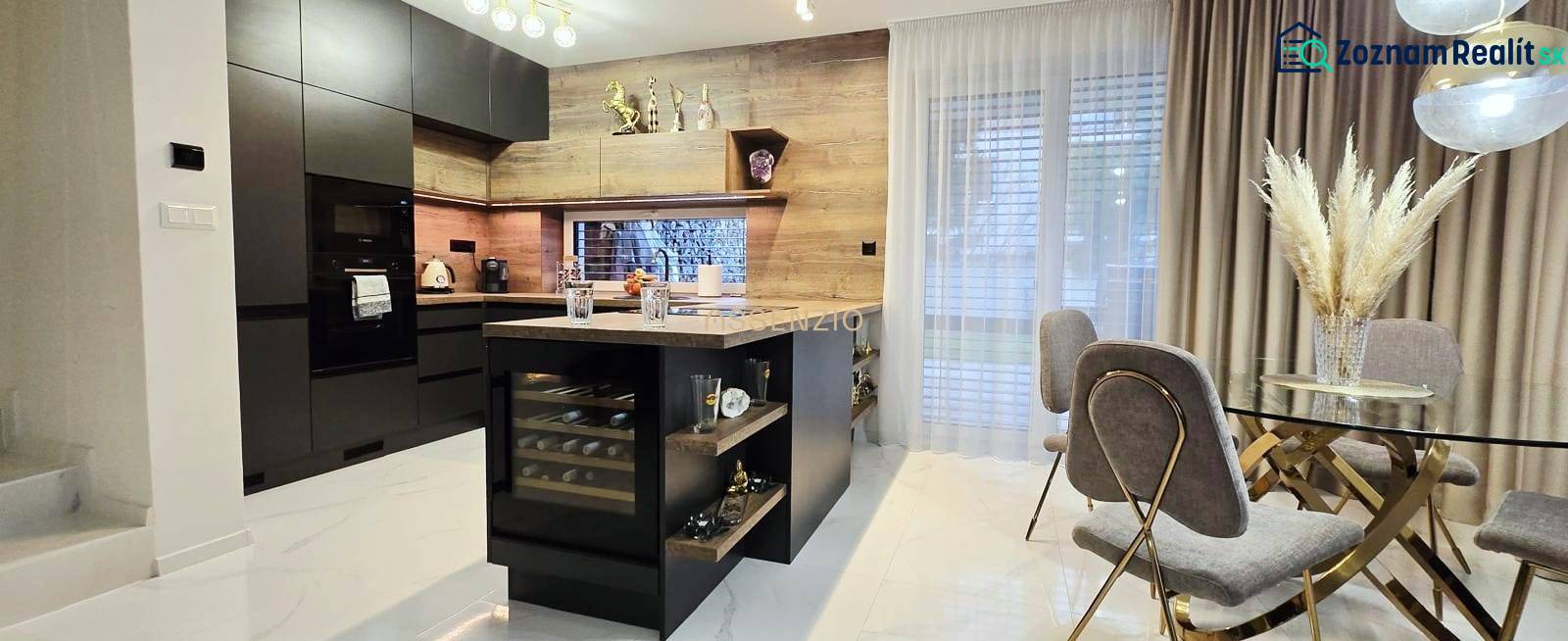 A kitchen in a family house with an island, black cabinets, and a wine cooler.