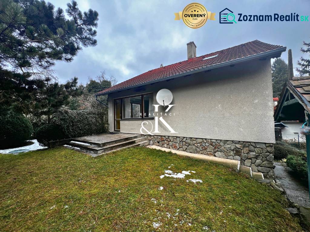 A cottage near Modra with a grassy plot, stone steps, and coniferous trees.