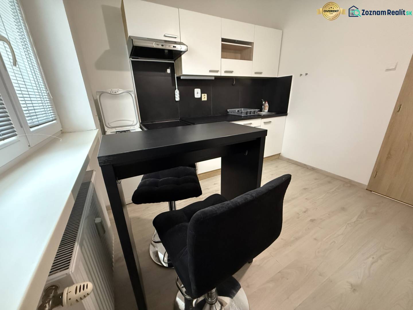 A kitchen with seating and a wooden decor floor in a studio apartment.
