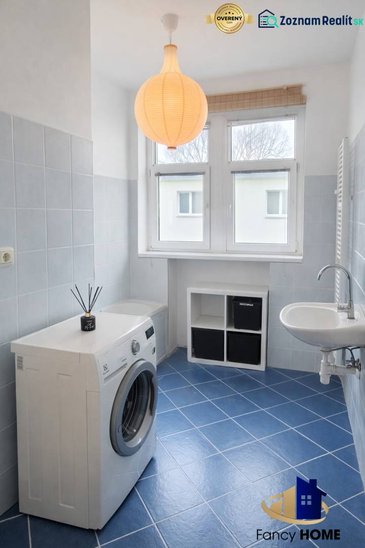 Bathroom in a 2-room apartment with a washing machine, sink, and blue tiles.
