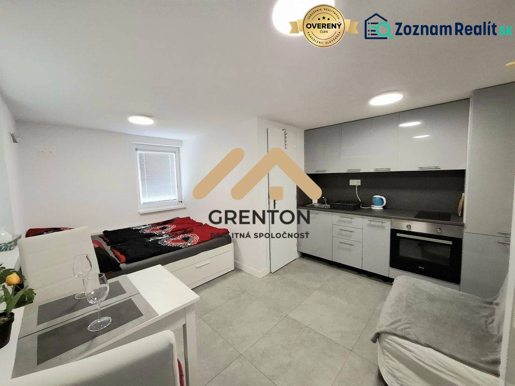 A kitchenette and a bed in a cabin with gray cladding and furnishings.