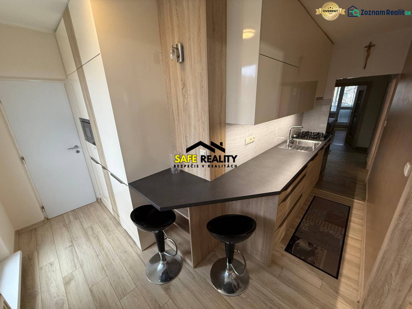 A kitchen in a 3-room apartment with a wooden decor floor and a dining counter.