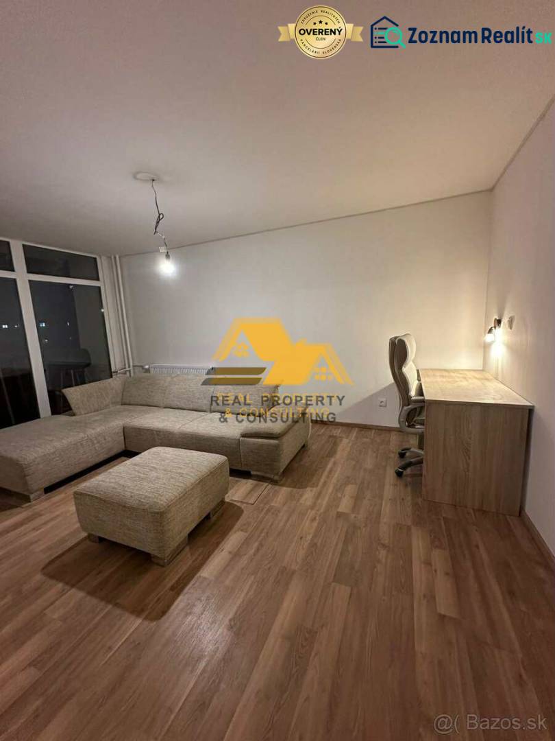 Living room of a two-room apartment with a wood-patterned floor, a corner sofa, and a table.