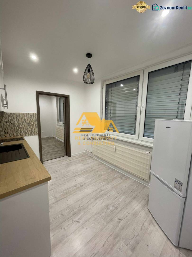 A kitchen in a studio apartment with a wood-patterned floor and white appliances.