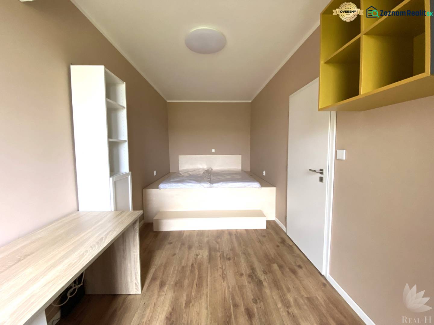 A room in a 3-room apartment with a wooden decor floor and a built-in desk.